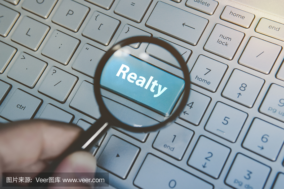 放大蓝色按钮Realty通过放大镜查看键盘背景。互联网财产搜索服务的概念。在网上寻找地产代理信息。电脑搜索房地产经纪人。
